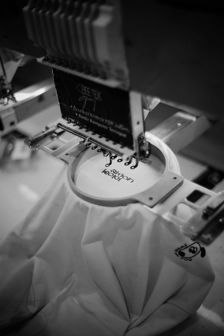 Máquina bordando un logotipo en tela blanca